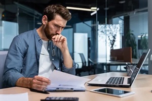 serious young man accountant, financier, analyst, auditor sits in the office at the table
