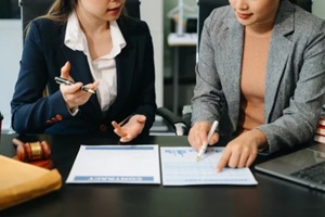 business and lawyers discussing contract papers with brass scale on desk in office