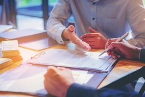 businessman puts signature on Termination For Convenience contract at business meeting and passing money after negotiations with business partners