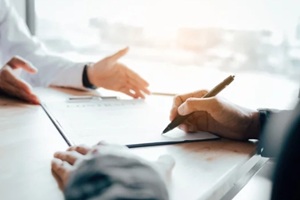client signing a real estate contract on desk in office