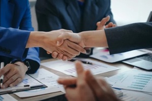 in a business team meeting, success is celebrated with a handshake