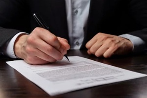 man signing contract papers