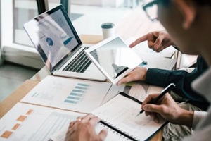 business partnership coworkers using a tablet to analysis graph company financial budget report and cost work progress and planning for future in office room