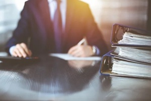 binders with papers are waiting to be processed by unknown man accountant in blue blazer staying at home during covid pandemic