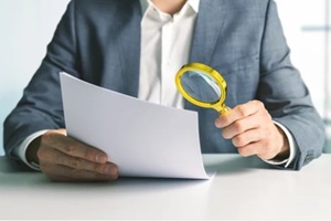 man checking documents with magnifying glass