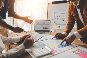 colleagues discuss business and analytical price charts using calculators and laptops to calculate financial, tax, accounting, statistics and analytical research ideas