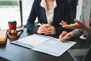 business and lawyers discussing contract papers with brass scale on desk in office